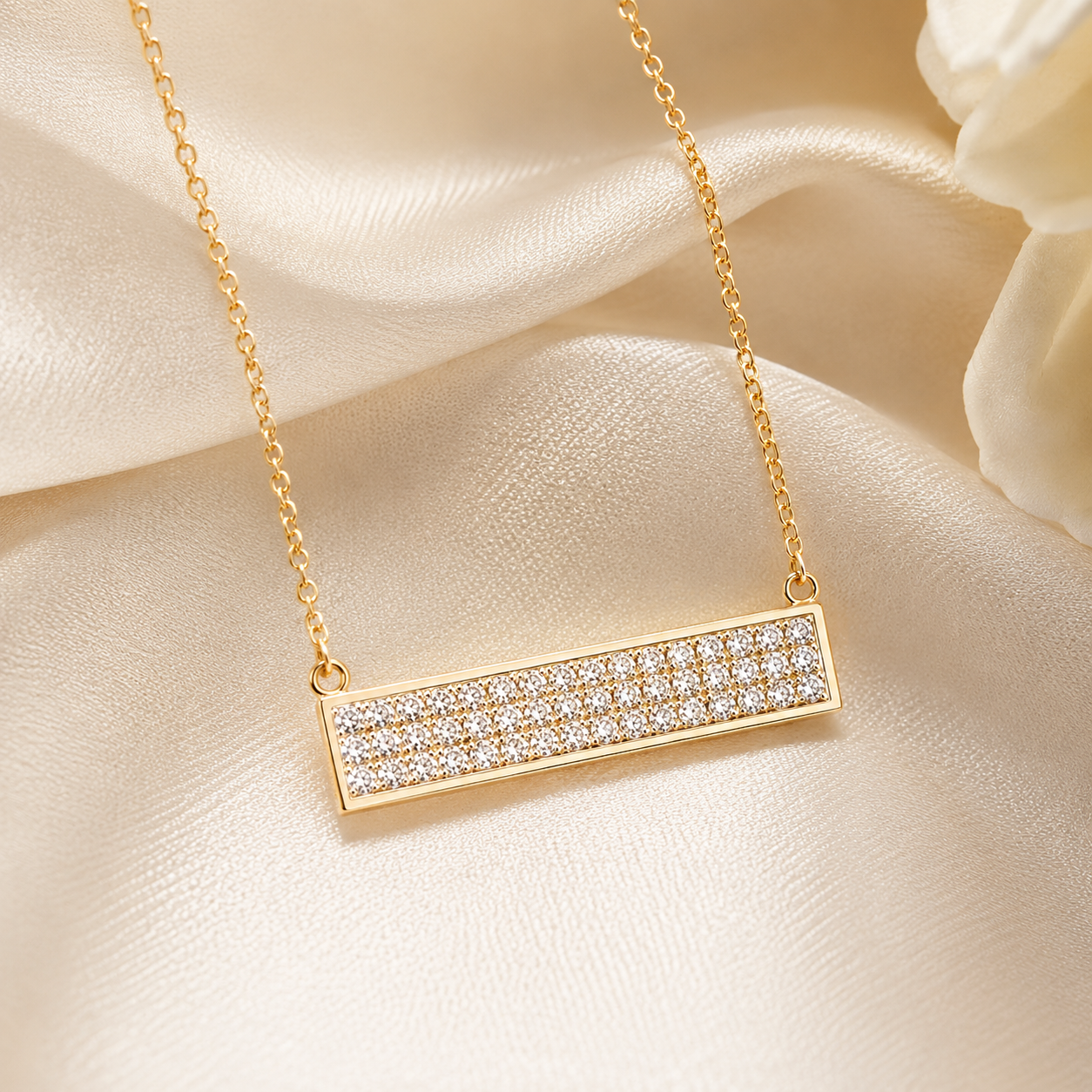 Gold necklace with a diamond-studded bar pendant on a beige background